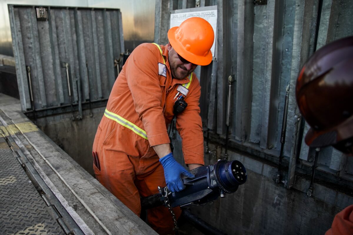 Mechanics prepare to connect a container ship to the TraPac terminal power grid.