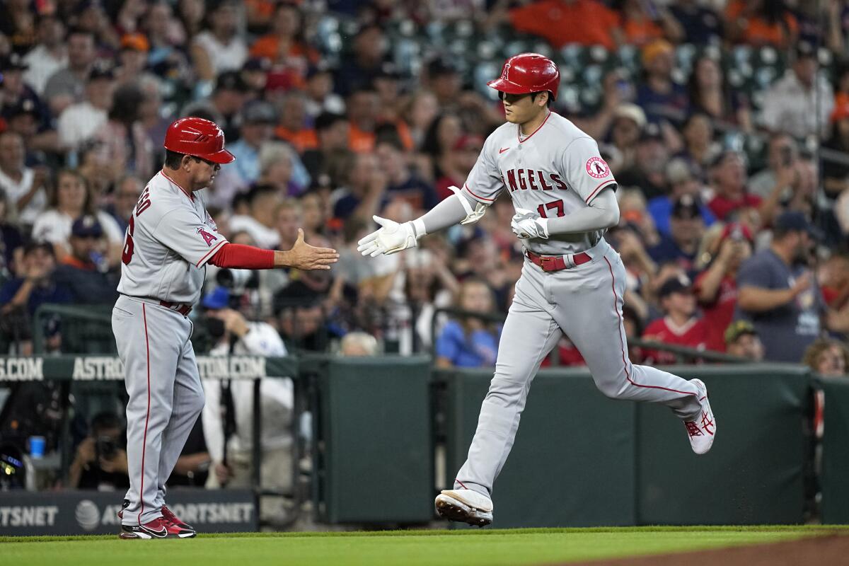 The Angels' Shohei Ohtani is congratulated by third base coach Mike Gallego after hitting a first-inning homer July 1, 2022.