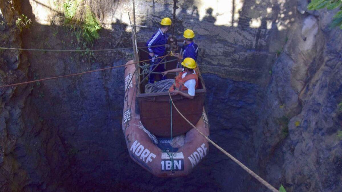 Indian navy divers are lowered into a mine with a pulley during rescue operations to help 15 men trapped by flooding in an illegal coal mine in Ksan village in northwestern India.