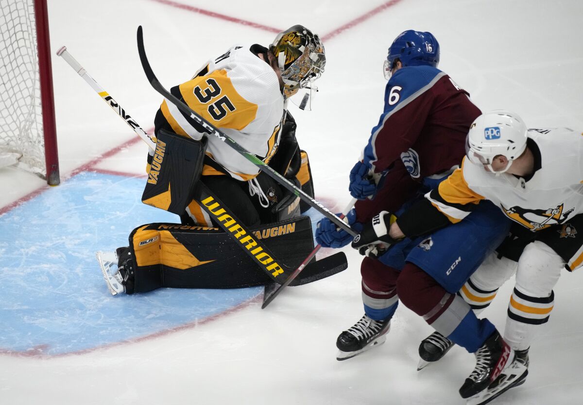 Colorado Avalanche right wing Nicolas Aube-Kubel, center, drives past Pittsburgh Penguins defenseman Mike Matheson, right, to shoot against Penguins goaltender Tristan Jarry in the third period of an NHL hockey game Saturday, April 2, 2022, in Denver. (AP Photo/David Zalubowski)