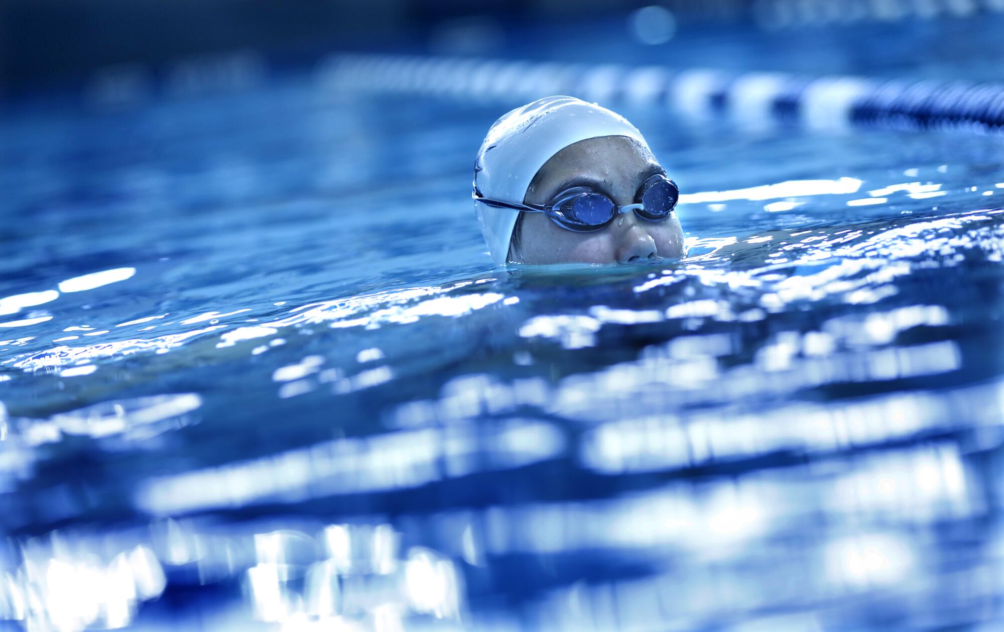 Kayla Han's head in a swim cap and goggles is mostly above water in a pool.