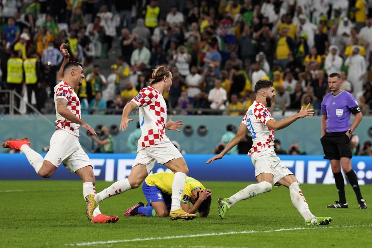 Brazil's Marquinhos lies on the ground as Croatia's player celebrate after the penalty shootout at the World Cup