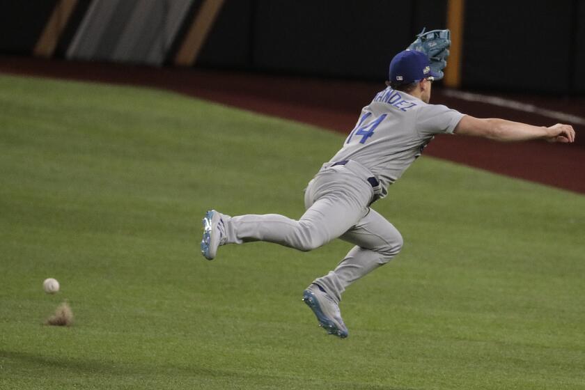 Arlington, Texas, Thursday, October 15, 2020. Los Angeles Dodgers second baseman Enrique Hernandez (14) can't grab an rbi single hit by Atlanta Braves second baseman Ozzie Albies (1) during a sixth inning rally in game four of the NLCS at Globe Life Field. (Robert Gauthier/ Los Angeles Times)