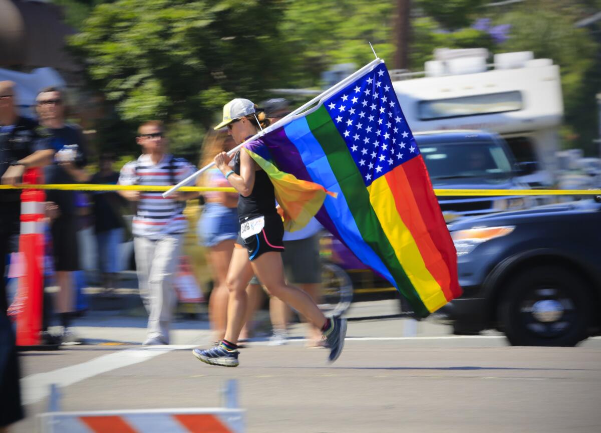 A runner carries a stylized American flag in the San Diego LGBT Pride 5K race on July 16, 2016.