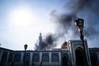 A trash fire billowing smoke above the Sayedah Zainab shrine