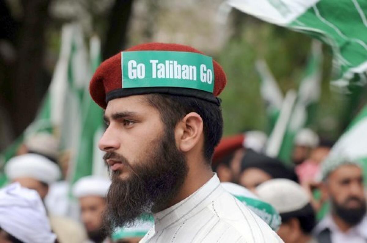 A protester in Islamabad wears a sign telling the extremist group to leave. Also seen are Go America Go signs.