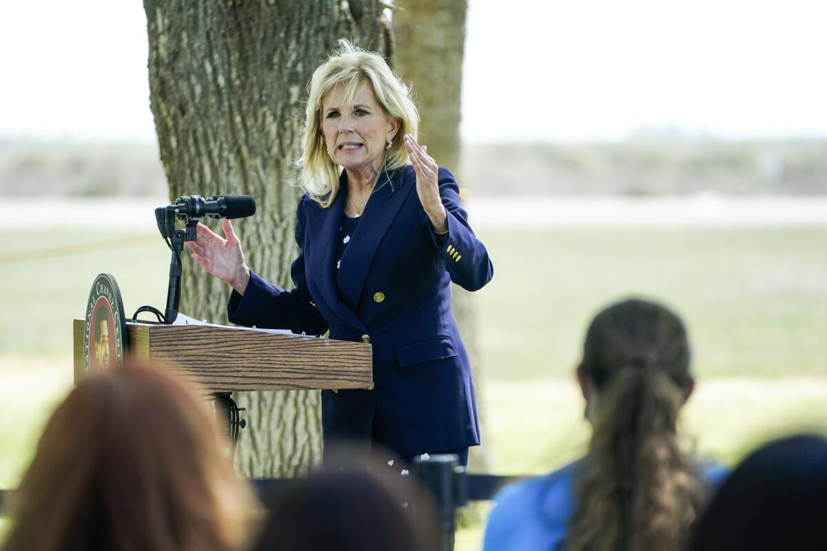 First Lady Jill Biden speaks at a lectern outdoors to an audience.