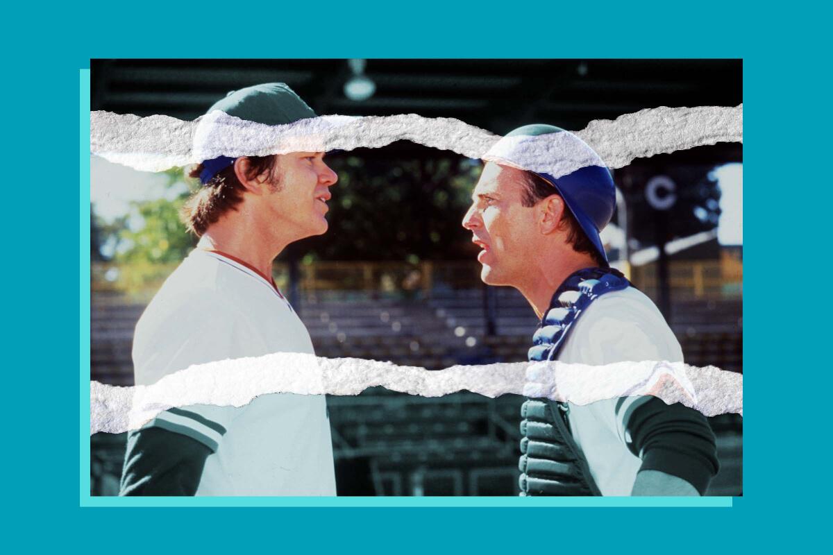 Two men in baseball uniforms speak on a baseball field.