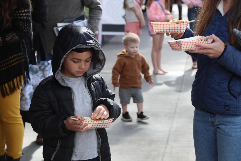 Kids gather around for frozen bananas at the iconic Sugar 'n Spice frozen banana stand on Balboa Island, Thursday.