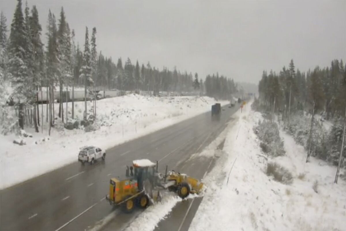 In this image from a Caltrans remote traffic video camera, snow is cleared from a shoulder lane along Interstate 80 at Donner Summit, Calif., Monday, Oct. 18, 2021. A cold front passing through drought-stricken California brought snow to the northern Sierra Nevada and rain, showers and drizzle elsewhere, the National Weather Service said Monday. The Sierra snowfall was significant enough to impact travel over the higher passes, the weather service said. (Caltrans via AP)