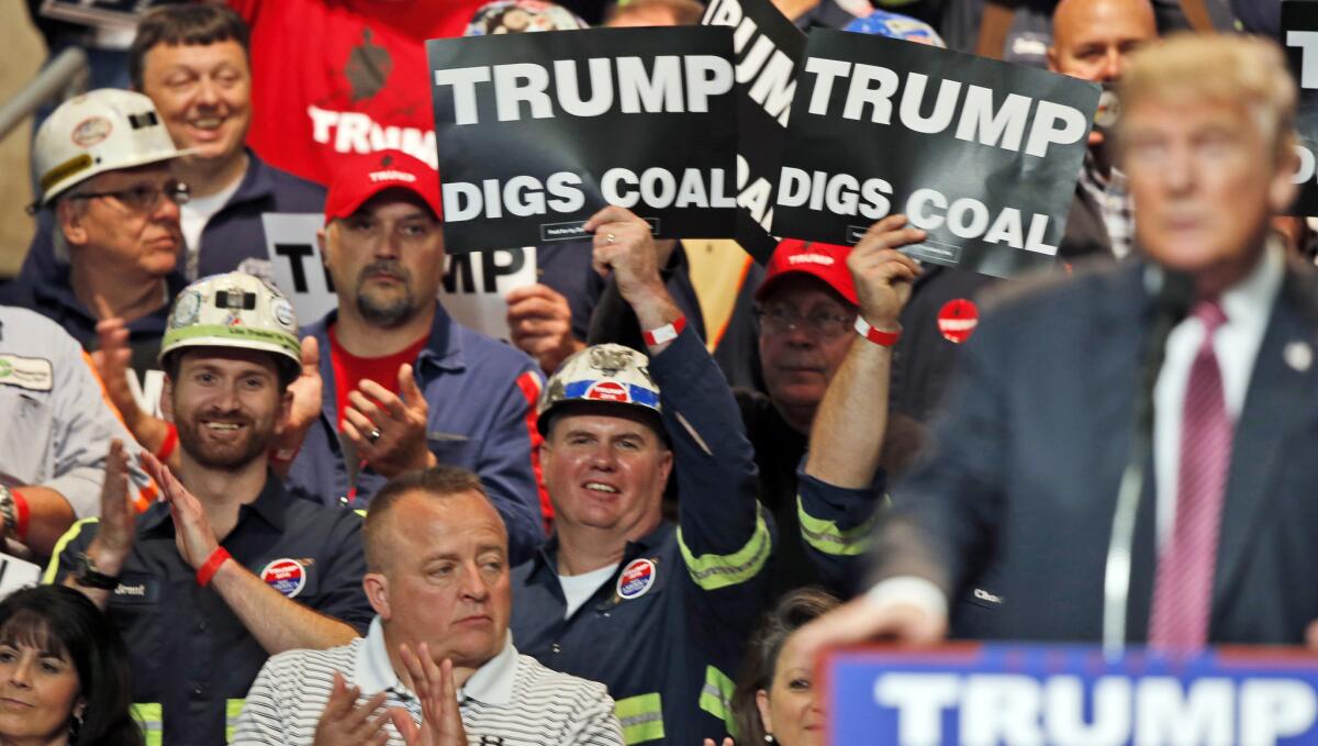 Coal miners wave signs as then-candidate Donald Trump speaks at a rally in Charleston, W.Va., in May 2016.