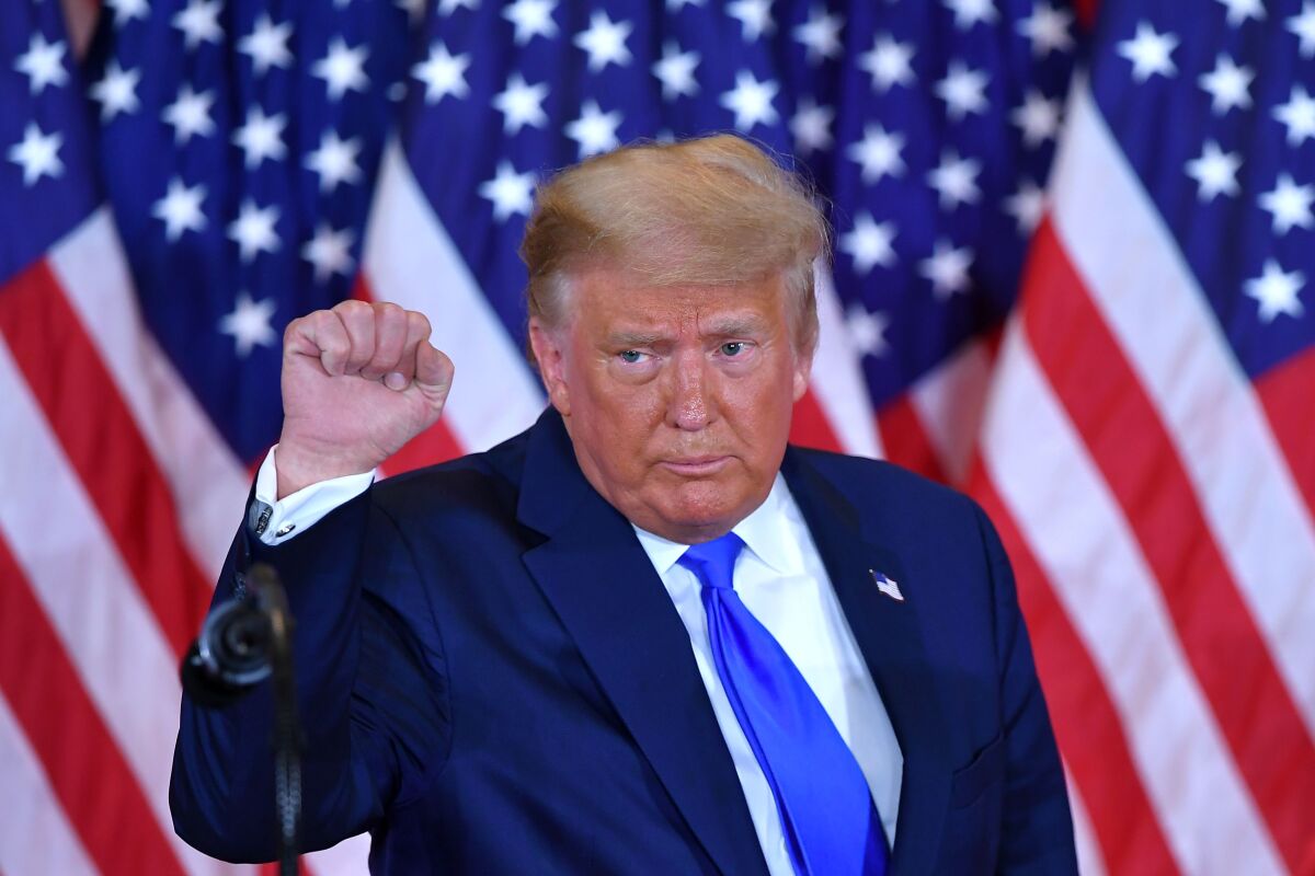 President Trump pumps his fist after falsely claiming election fraud during an election night speech in the White House.