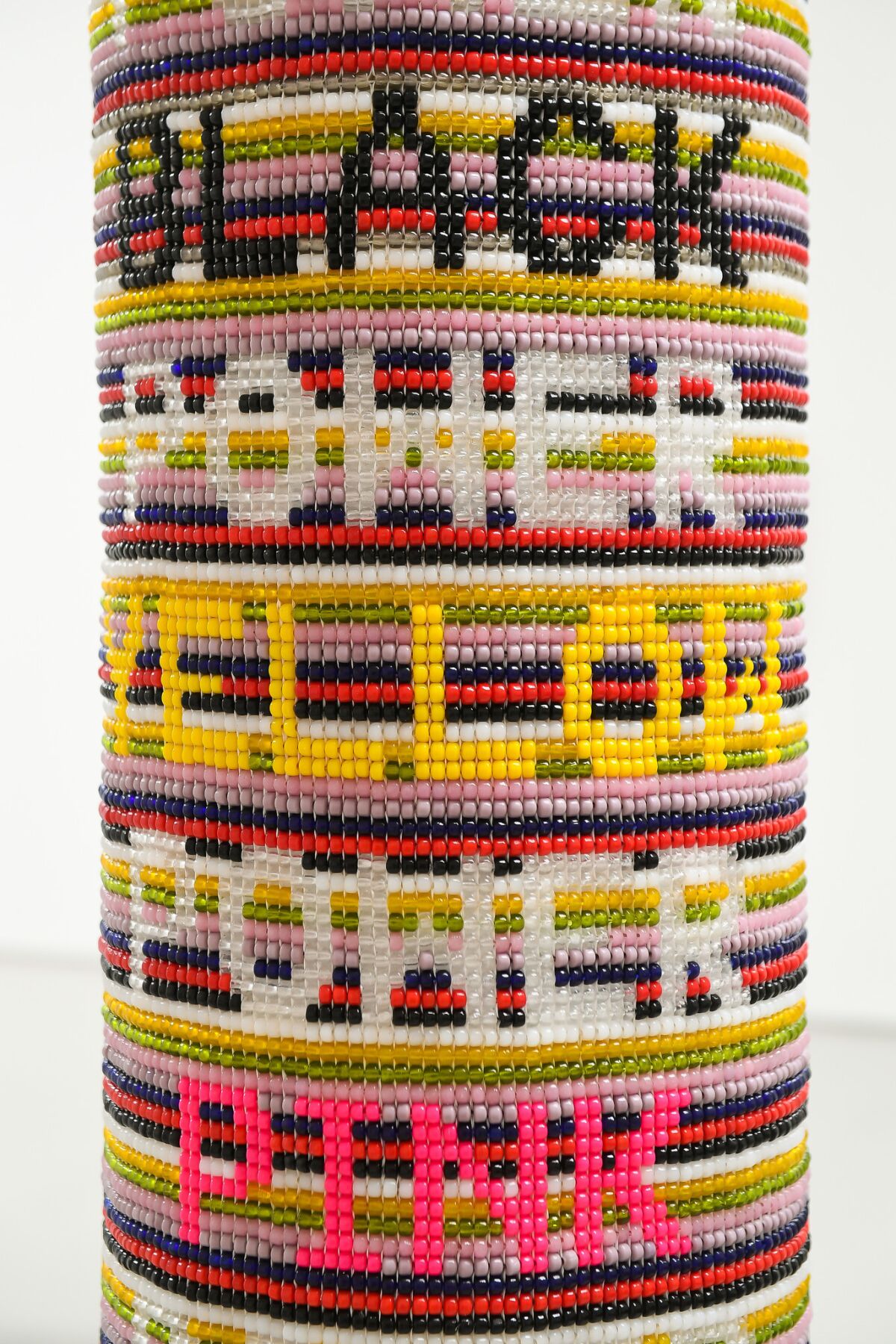 Detail of Jeffrey Gibson's "Power Power Power." The full piece reads, "black power yellow power pink power blue power." 2017, repurposed vinyl punching bag, glass beads, artificial sinew, acrylic felt. 51 inches by 12 inches.