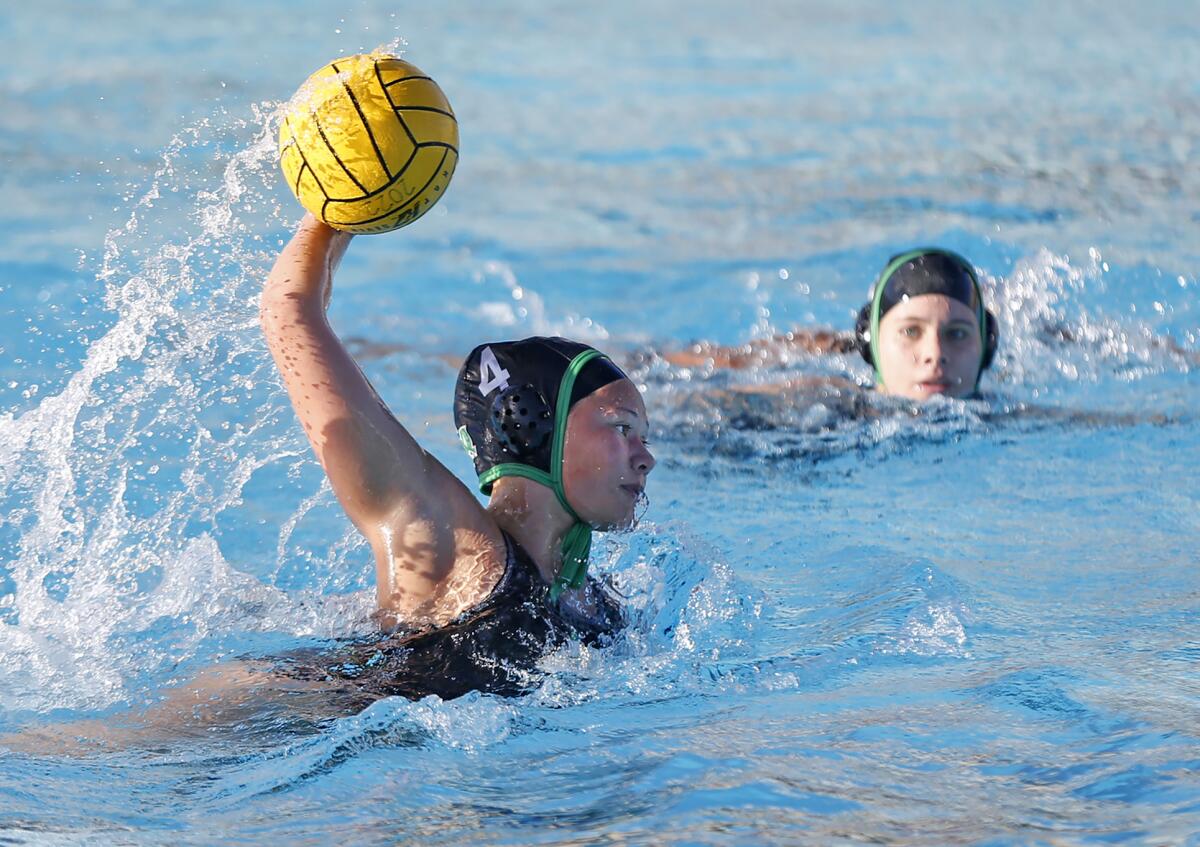 Costa Mesa's Dharma Andreas (4) shoots and scores during the Battle for the Bell girls' water polo game against Estancia.
