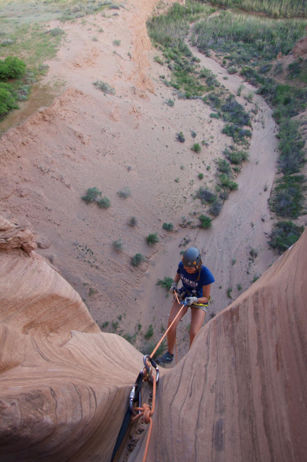 A woman holds on to a rope 100 feet above the canyon floor