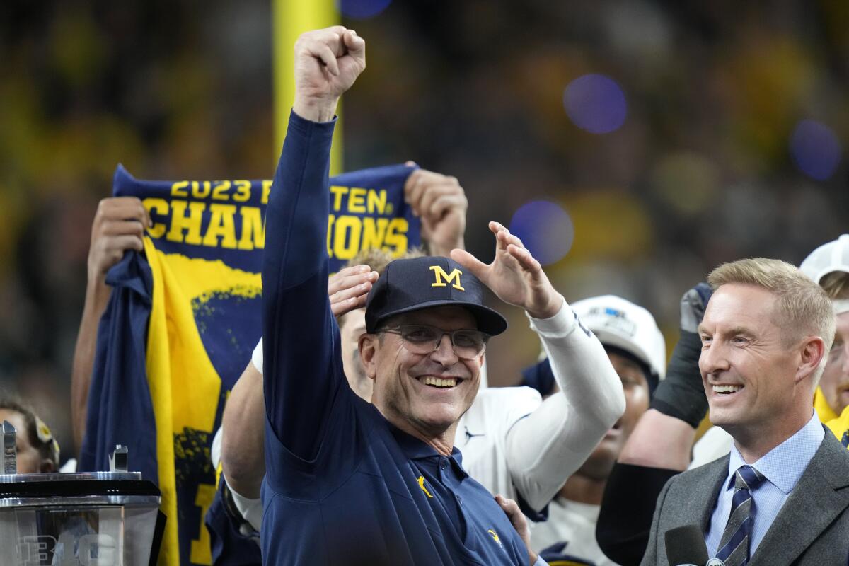 Jim Harbaugh raises a fist and smiles.