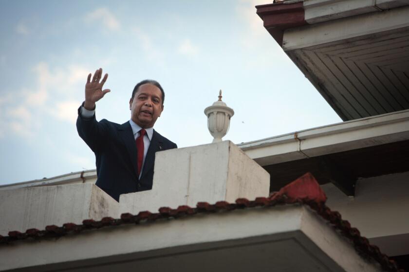 Former Haiti dictator Jean-Claude "Baby Doc" Duvalier waves from a balcony after a news conference at his house in in Port-au-Prince, Haiti, in 2010. Duvalier had returned from exile and was questioned by authorities before being released.