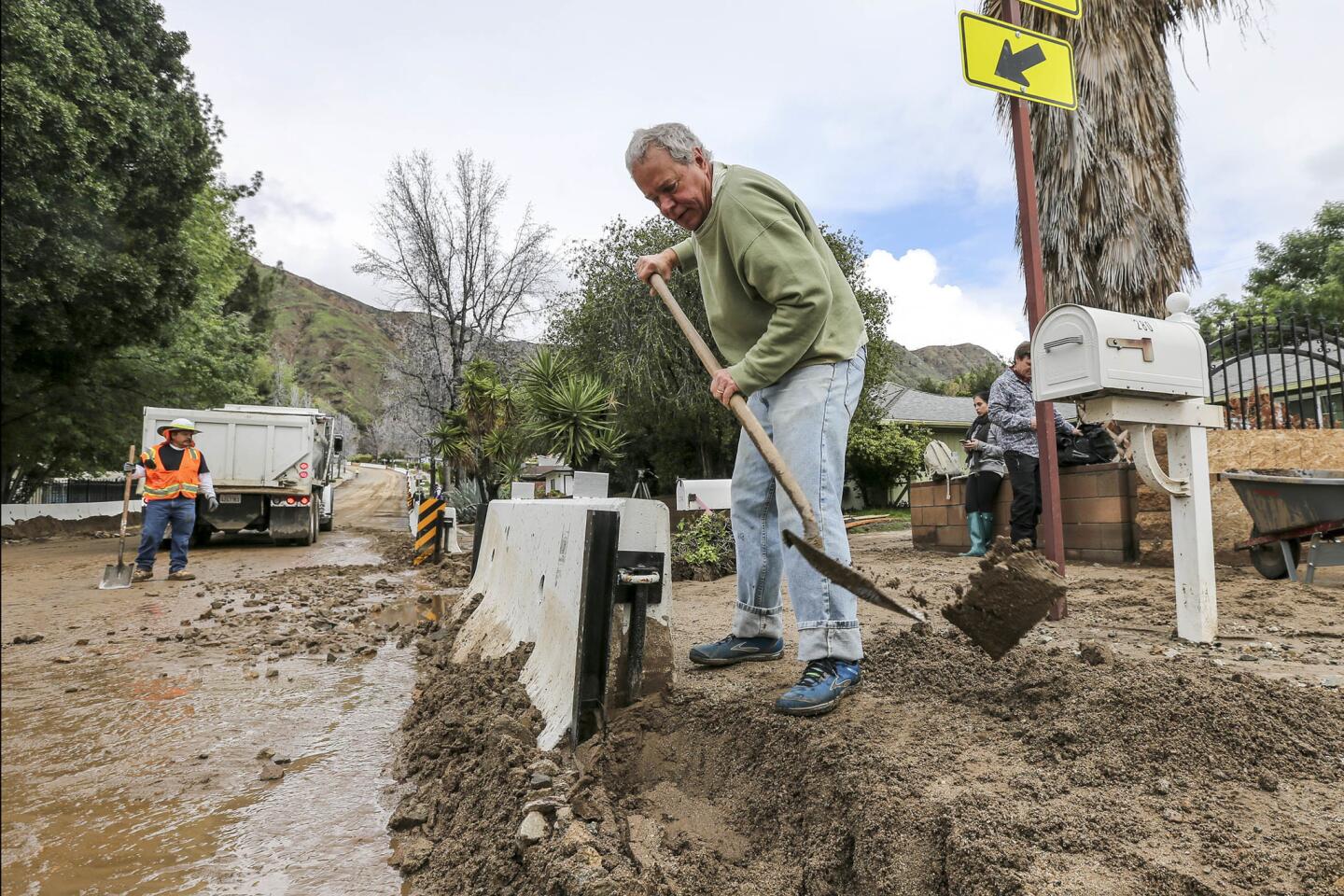Richard Walker clears mud accumulated on his drive on Melcayon Road caused by last night's heavy rain in Duarte.