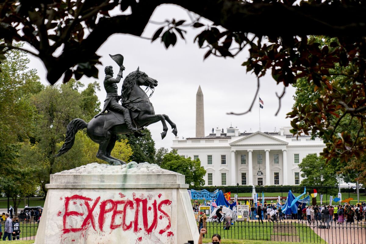 The words "Expect Us" are spray painted on the base of the Andrew Jackson statue in Lafayette Park as Indigenous and environmental activists protest in front of the White House in Washington, Monday, Oct. 11, 2021. The words are part of the phrase "Respect Us, or Expect Us" which indigenous women have been using while protesting oil company Enbridge's Line 3 pipeline through Minnesota. President Joe Biden on Friday issued the first-ever presidential proclamation of Indigenous Peoples Day, lending the most significant boost yet to efforts to refocus the federal holiday celebrating Christopher Columbus toward an appreciation of Native peoples. (AP Photo/Andrew Harnik)