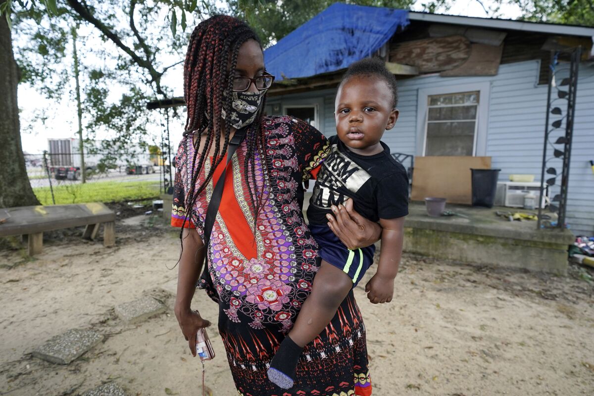 Fakisha Fenderson and her son Tyler stand in the front yard of her parent's home in Laurel, Miss., Monday, Aug. 31, 2020. Fenderson's weekly unemployment allotment is under $100, effectively eliminating her chance at receiving the $300 weekly supplement proposed by President Trump's executive order. (AP Photo/Rogelio V. Solis)