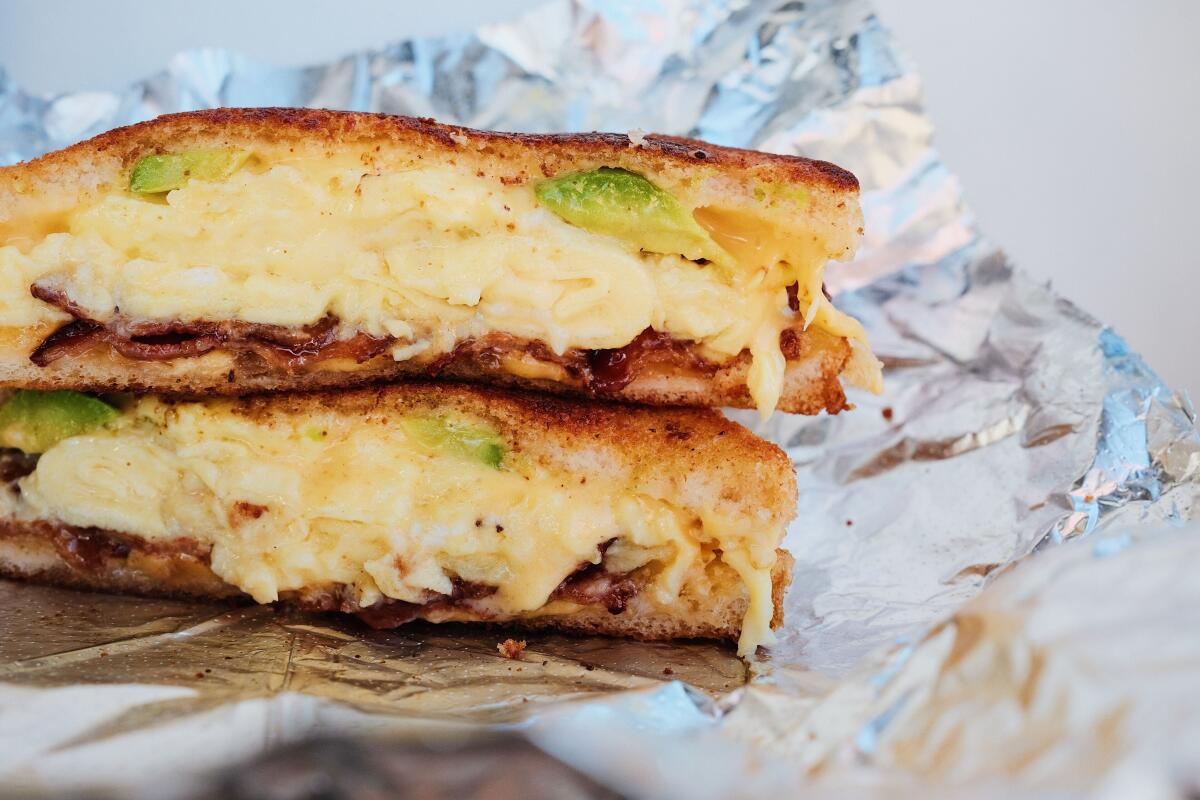 A closeup of two stacked halves of a Calabama breakfast sandwich featuring eggs, bacon and avocado