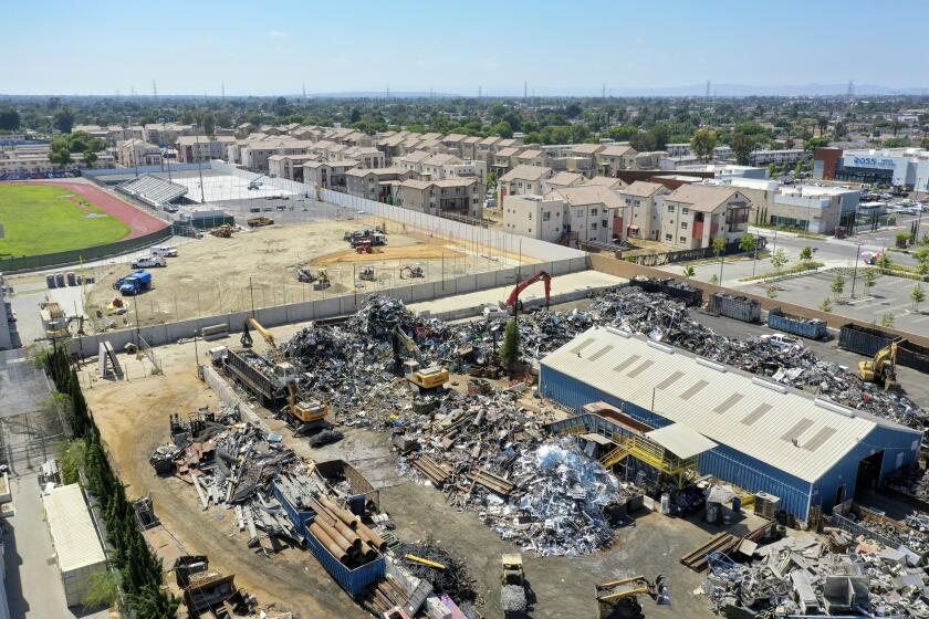WATTS, CA - JUNE 16: An aerial view of Atlas Iron & Metal Co., which is a metal recycler that has piles of metal scrap and debris adjacent to newly-built Jordon Downs public housing, shown at top right of photo, and Jordan High School Tuesday, June 16, 2020 in Watts, CA. (Allen J. Schaben / Los Angeles Times)