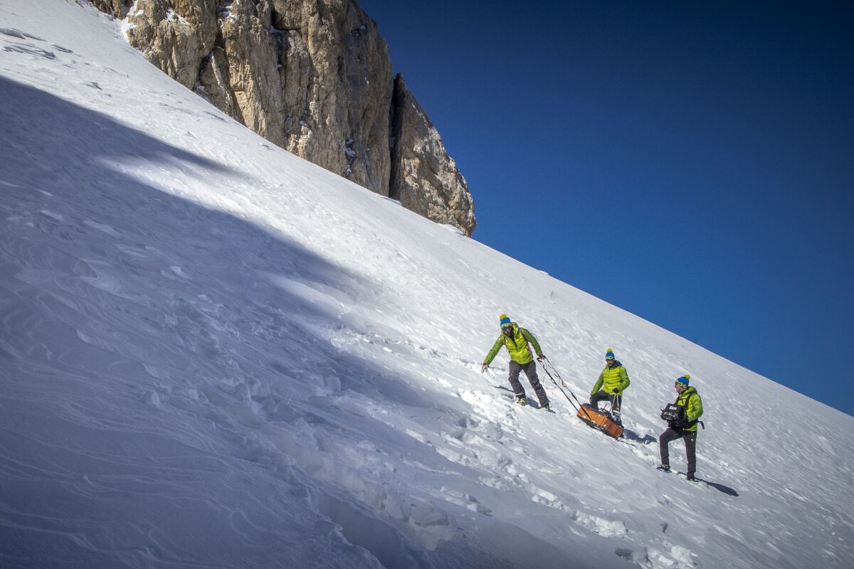 In this photo provided by CNR and Ca Foscari University, scientists haul an ice scanner on the slopes of the Mt. Gran Sasso d'Italia in central Italy, Sunday, March 13, 2022. Italian scientists are racing against time to study, scan and sample Europe’s southern-most glacier before it melts and disappears as a result of rising global temperatures. Researchers conducted a preliminary radar survey of the Calderone glacier in Italy’s central Apennine Mountains on March 13 and plan to return next month to drill into it and take samples. (Riccardo Selvatico/CNR and Ca Foscari University via AP)