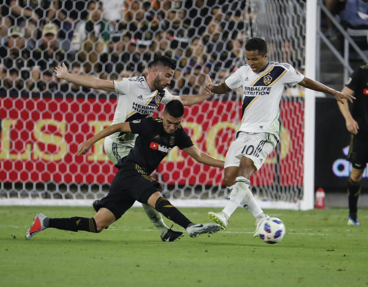Galaxy midfielder Romain Alessandrini, left, and forward Giovani dos Santos, right, battle LAFC midfielder Eduard Atuesta, center, for control of the ball in the second half against the LAFC at the Banc of California Stadium.