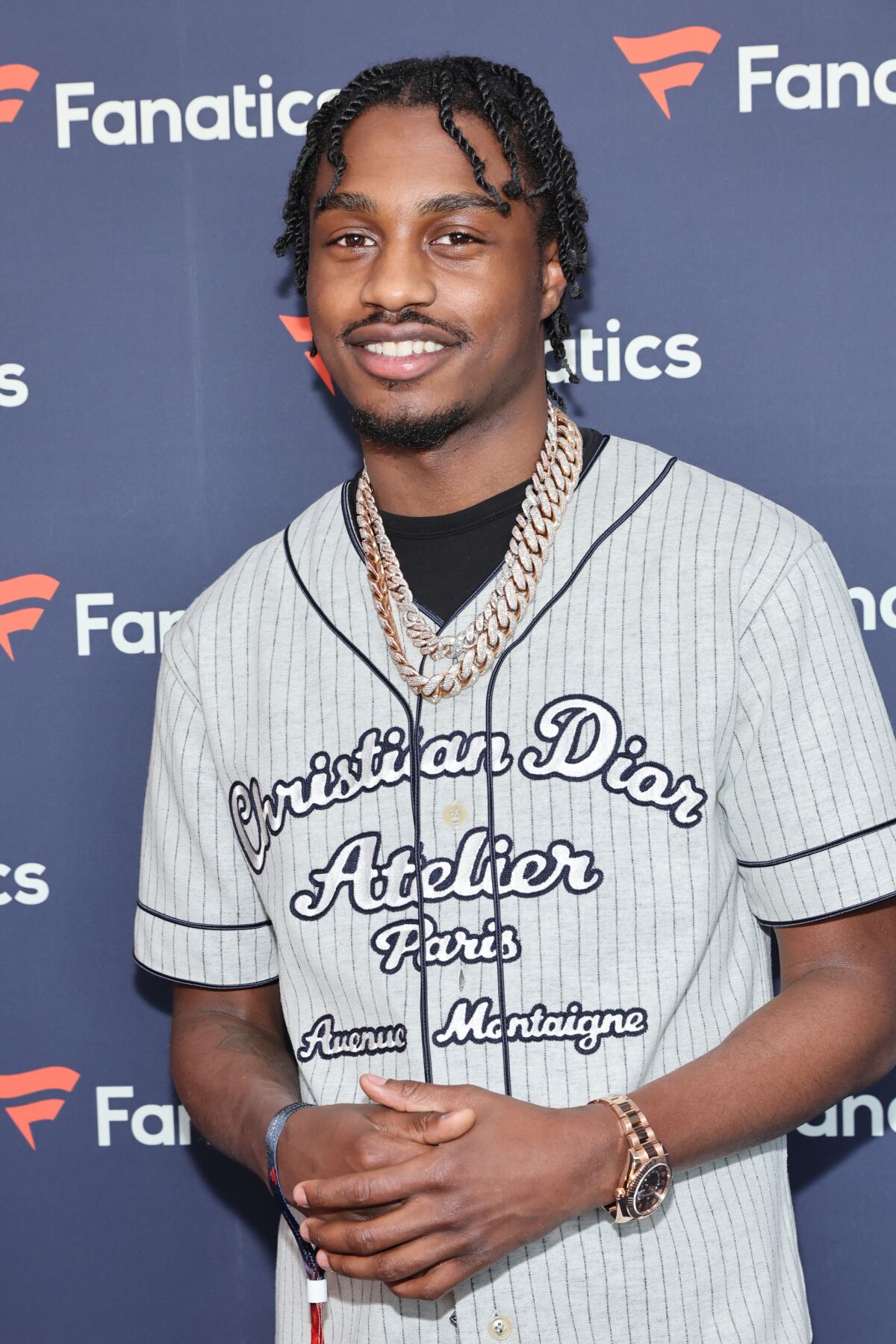 A man wearing a baseball jersey and gold chain
