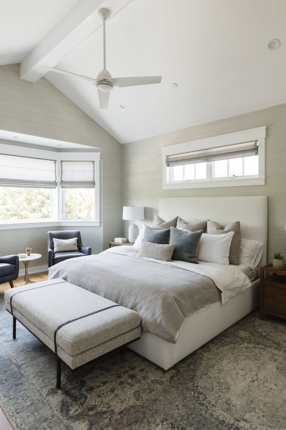 A Coronado bedroom in tone-on-tone colors has a sitting nook by a bay window and a bench at the foot of the bed.