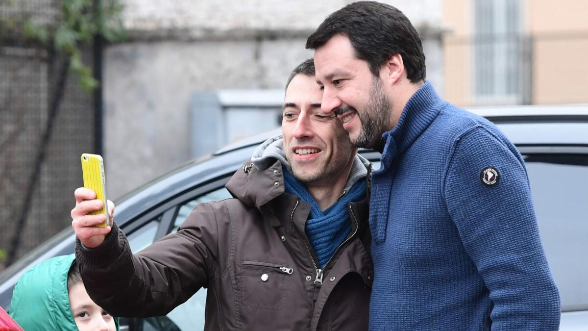 Far-right League party leader Matteo Salvini, right, poses for a selfie with a supporter as he arrives to vote for general elections at a polling station in Milan on March 4, 2018.