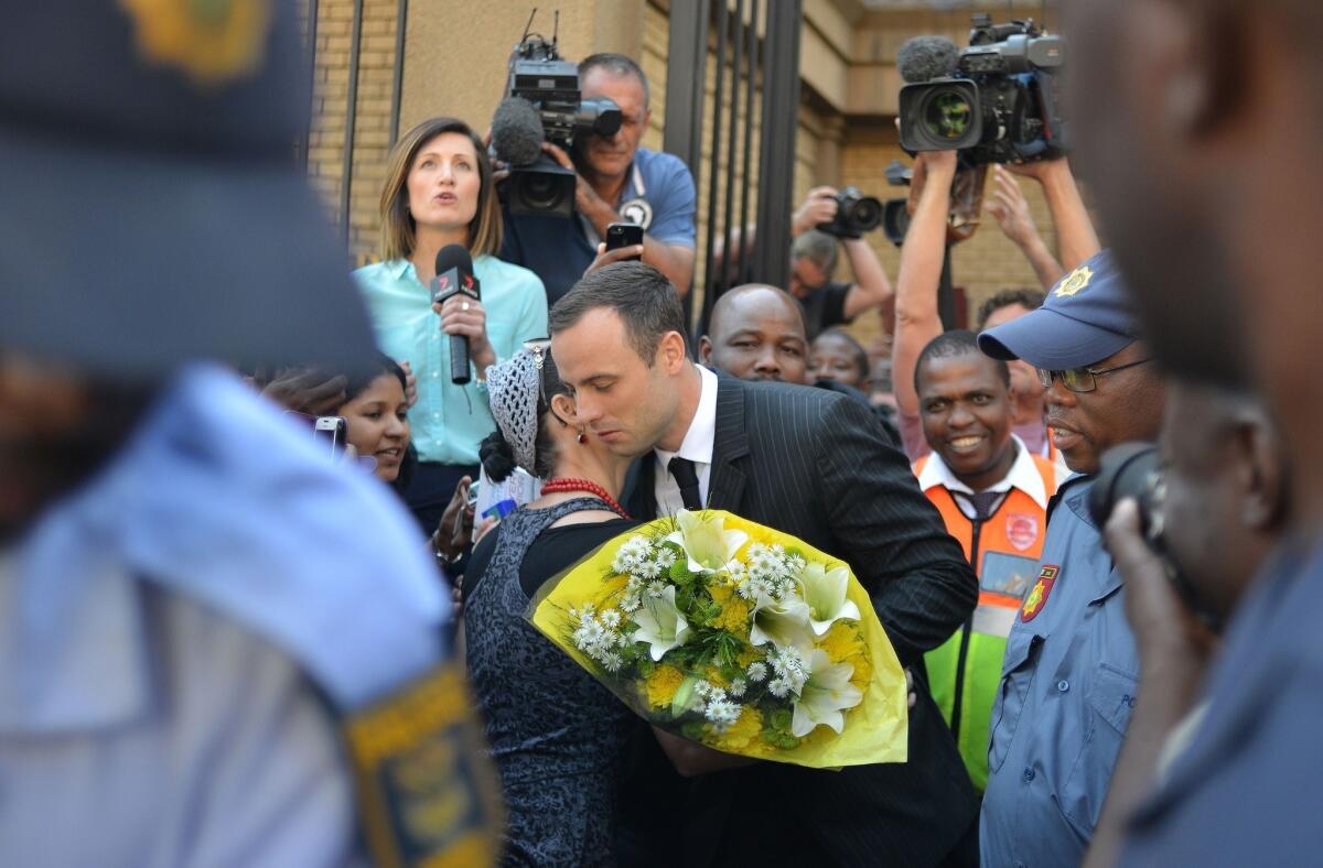 A woman hugs South African athlete Oscar Pistorius after handing him flowers as he leaves court in Pretoria on Friday.