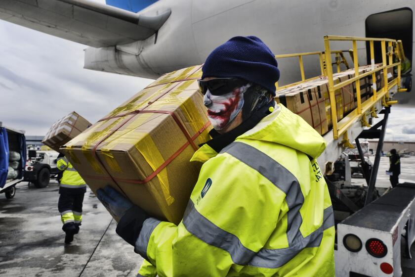 FILE - In this April 10, 2020, file photo, wearing protective masks ground crew at the Los Angeles International airport unload supplies of medical personal protective equipment from a China Southern Cargo plane. Three million surgical masks arrived in California last weekend as the first shipment in a major deal cut by California Gov. Gavin Newsom for 200 million masks per month to protect health care and other workers from the coronavirus.. (AP Photo/Richard Vogel, File)