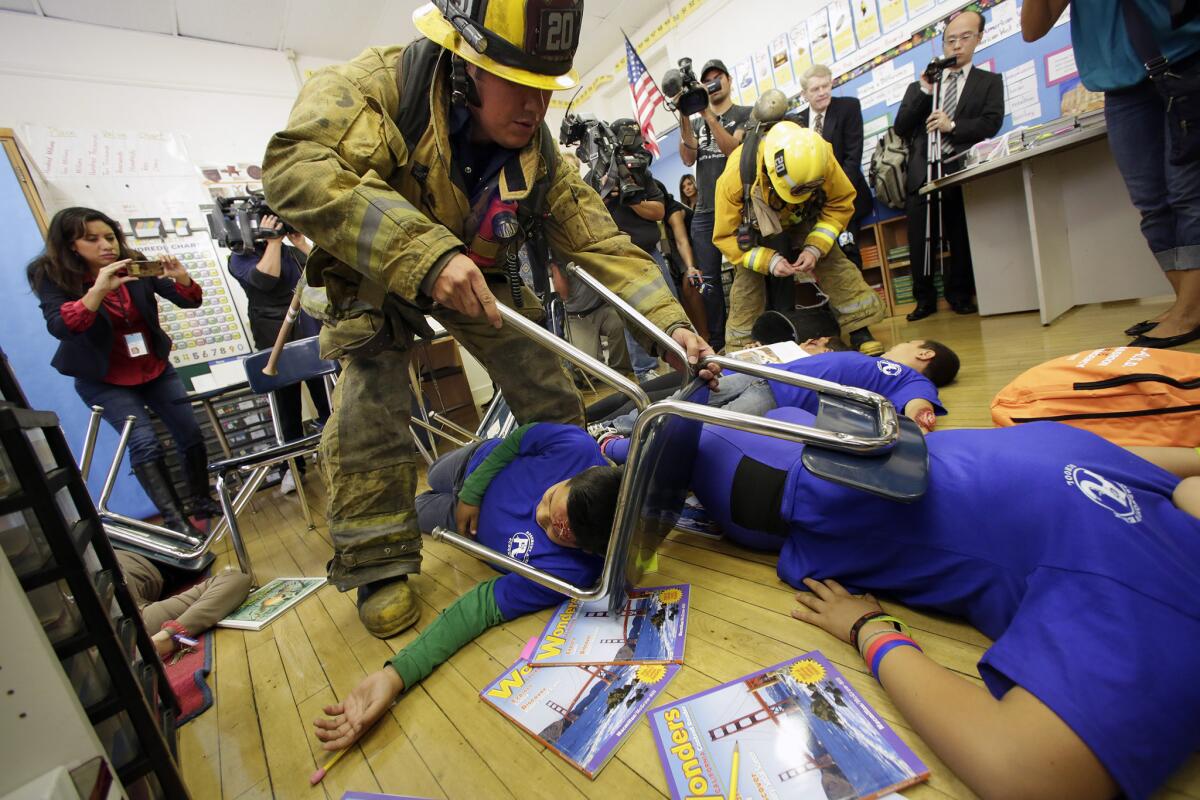 Firefighters practice rescuing students with fake injuries during an earthquake drill at Rosemont Avenue Elementary School in Echo Park last year.