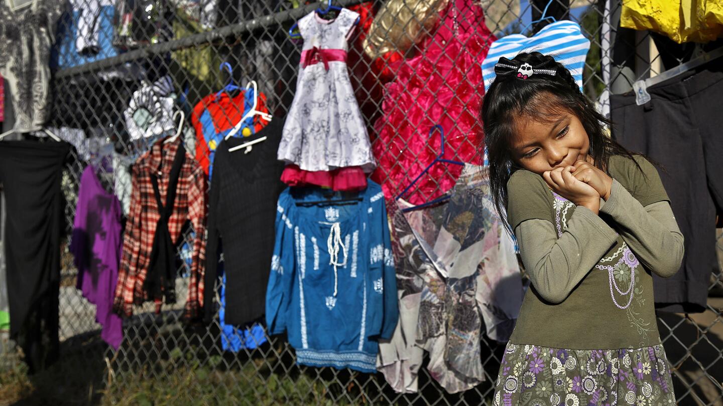 Clarissa Quintero, 5, plays among the clothing available for sale in Carmen Quintero's large yard sale, which she holds in order to stay home and watch over her children.