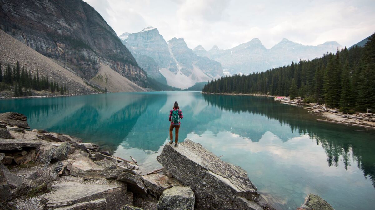 A woman stands on a scenic point overlooking Moraine Lake in Banff National Park in Alberta, Canada.