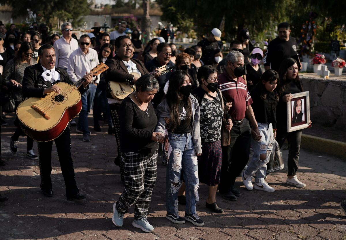 Mariachi musicians play music during a funeral procession.