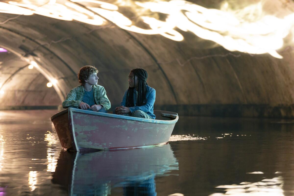 A boy and girl sitting in a canoe in an underground water tunnel.