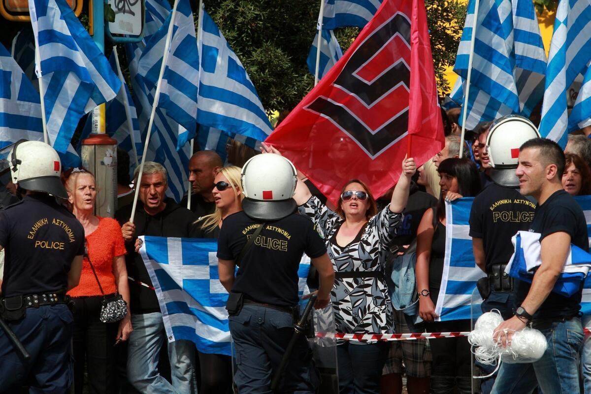 Supporters of the ultra-right Greek political party Golden Dawn wave the national flag and the swastika-like party banner outside an Athens courthouse as they await the release on bail of party leaders accused of organizing a criminal enterprise.