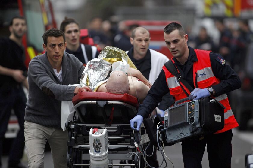 An injured person is evacuated outside the French satirical newspaper Charlie Hebdo's office, in Paris on Jan. 7, 2015.