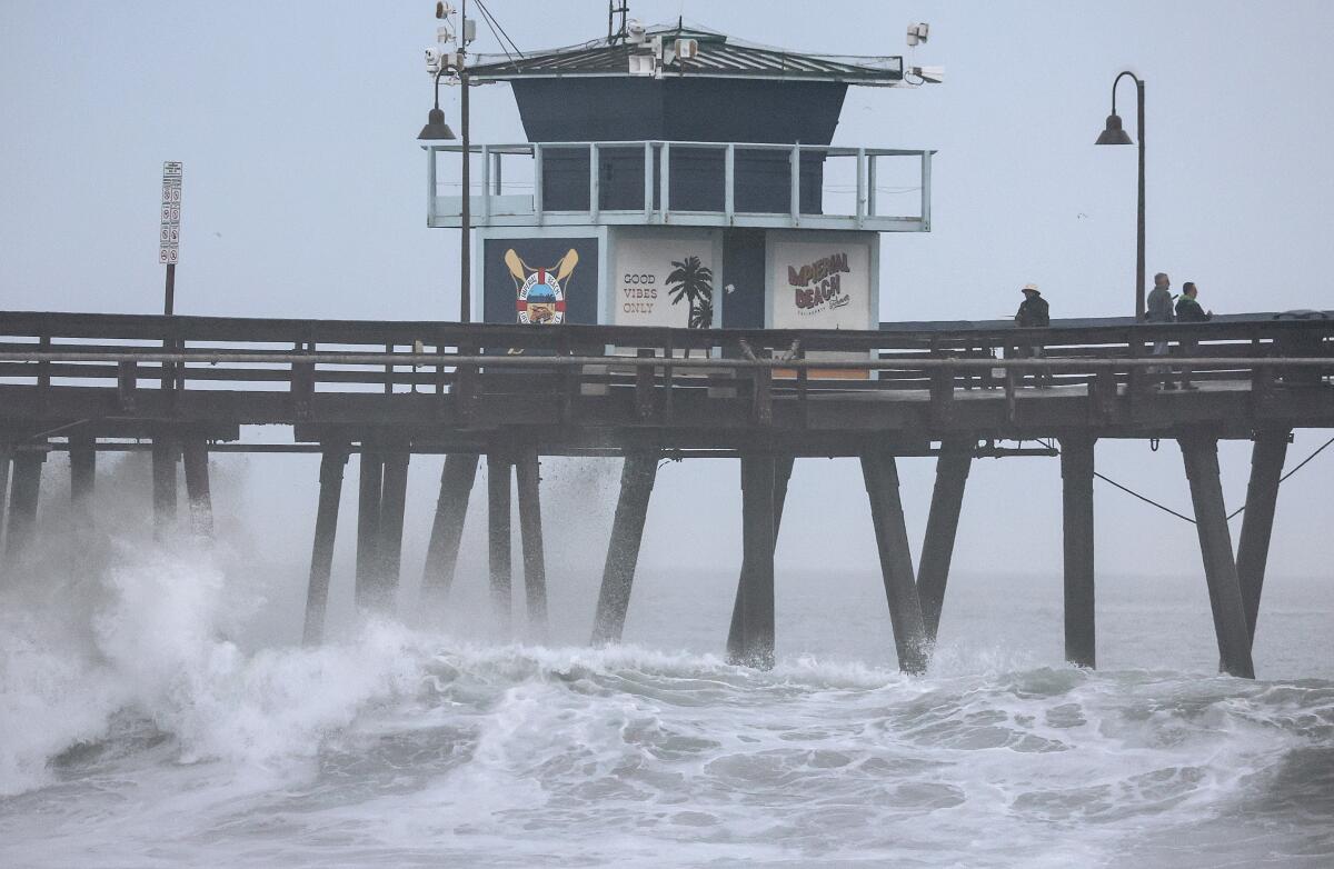 People stand on a pier over the Pacific Ocean with Tropical Storm Hilary approaching in Imperial Beach.