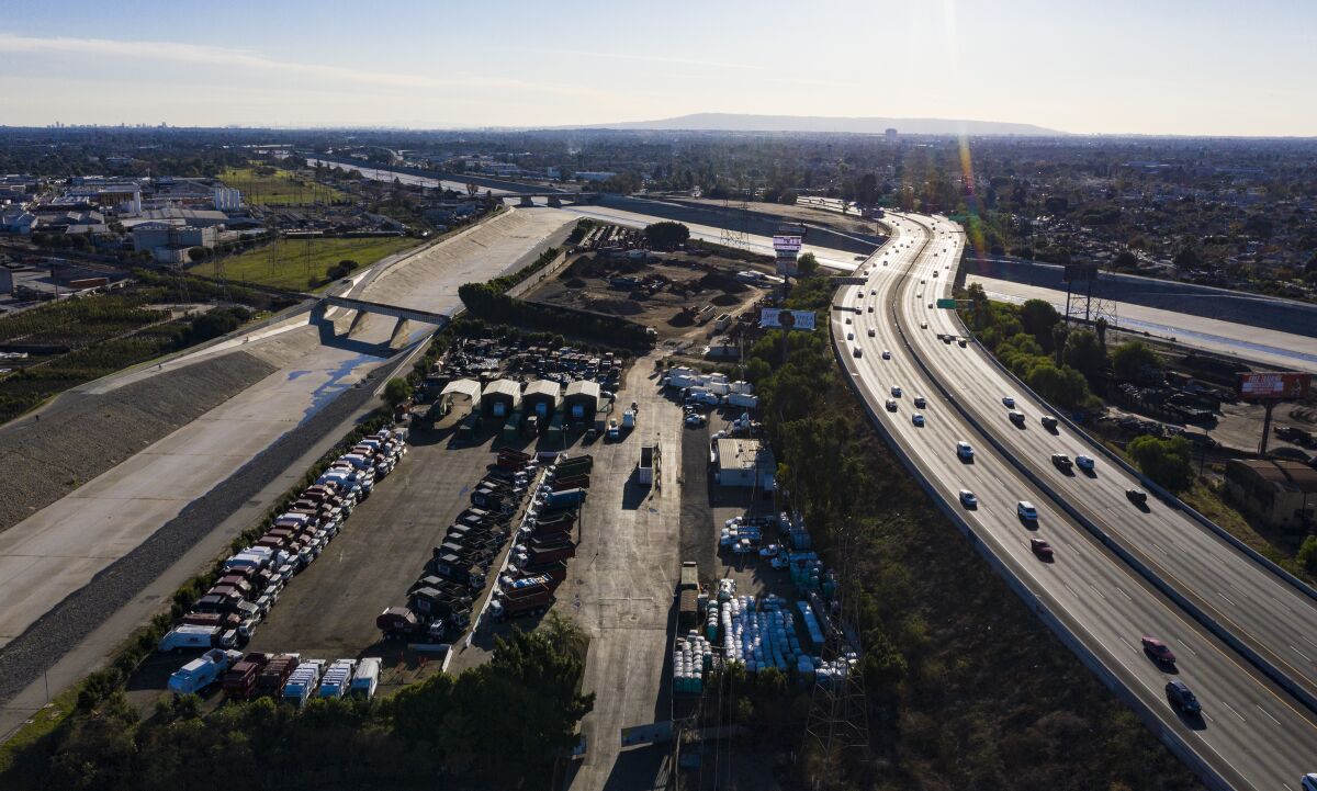 An aerial view takes in the 710 Freeway, with scattered cars, and the dry L.A. River.