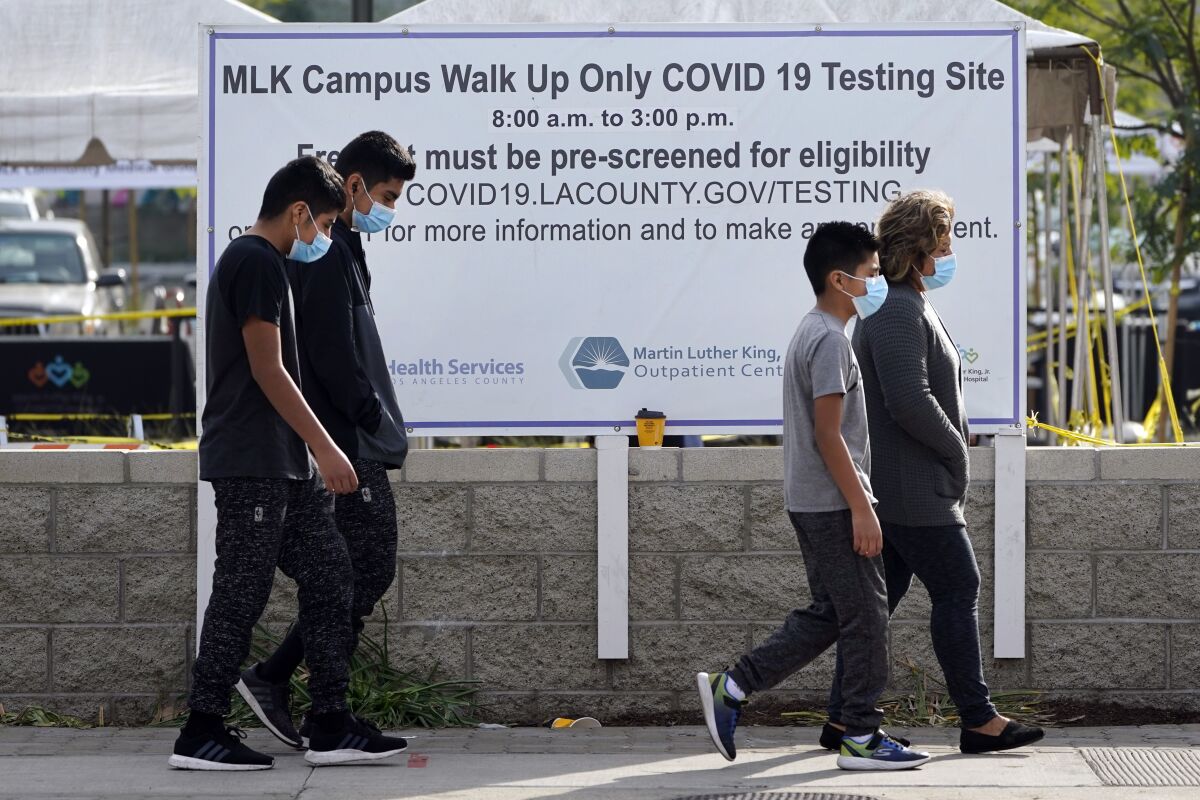 Masked pedestrians walk past a COVID-19 testing site on the Martin Luther King Jr. Medical Campus Thursday, Jan. 7, 2021, in Los Angeles. (AP Photo/Marcio Jose Sanchez)