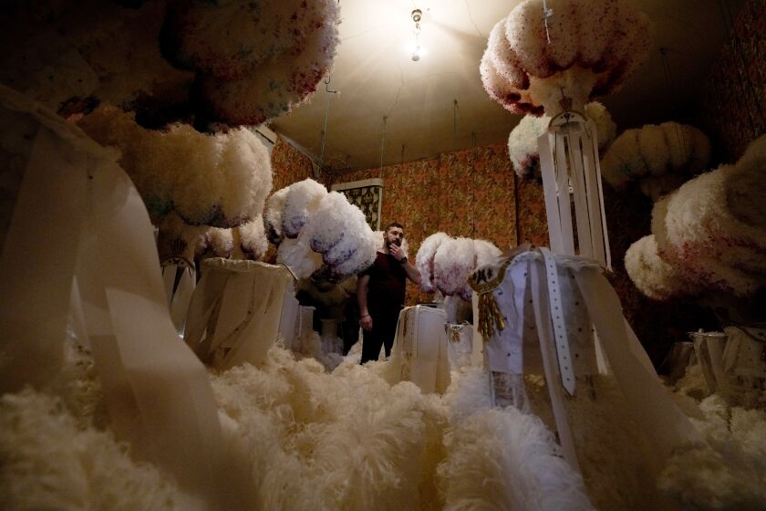 Quentin Kersten stands in the middle of a room full of ostrich feather hats in the Kersten family costume workshop in Binche, Belgium, Wednesday, Feb. 1, 2023. After a COVID-imposed hiatus, artisans are putting finishing touches on elaborate costumes and floats for the renowned Carnival in the Belgian town of Binche, a tradition that brings together young and old and is a welcome moment of celebration after a rough few years. (AP Photo/Virginia Mayo)