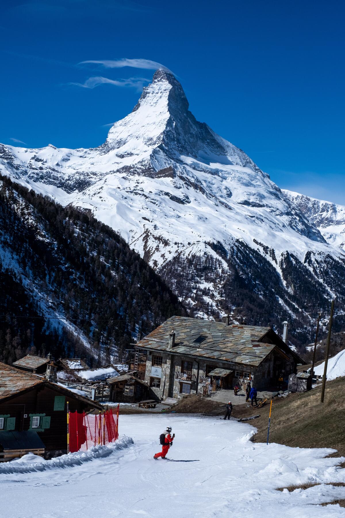 A snowboarder heads through Alpine villages below the Matterhorn.