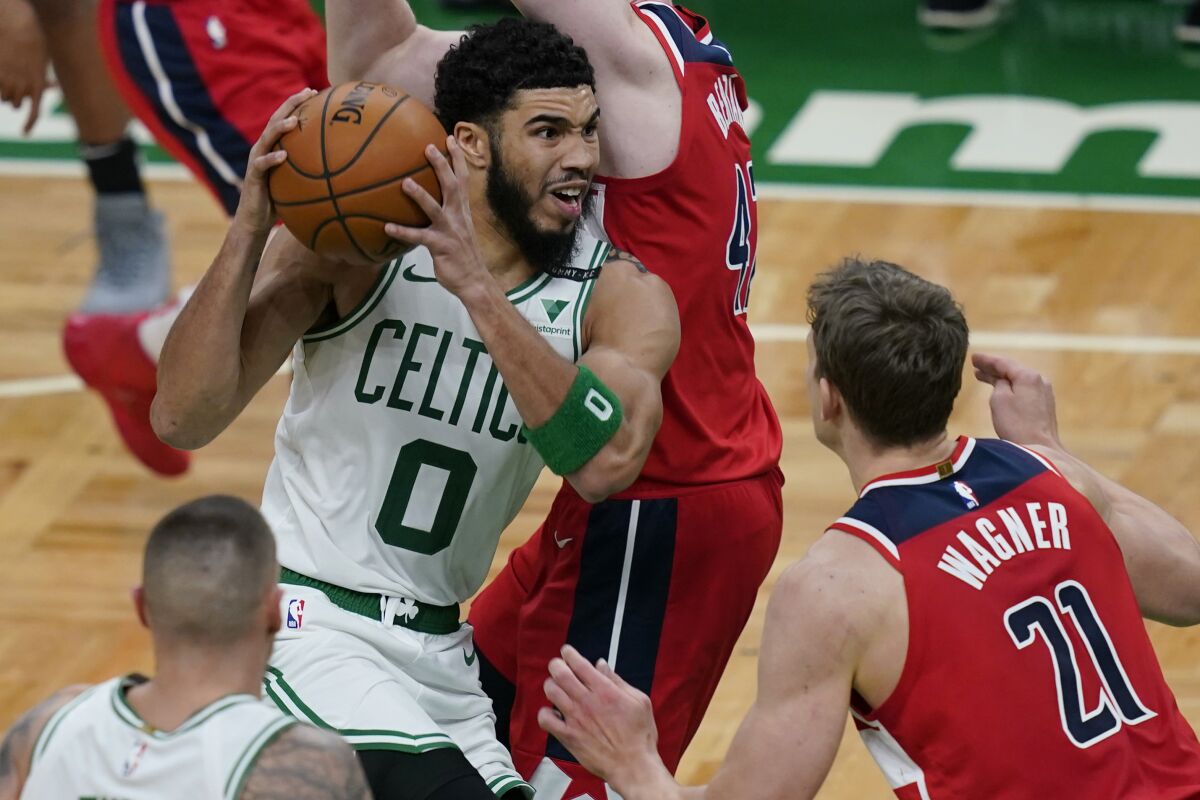 Celtics forward Jayson Tatum drives against Wizards forward Davis Bertans and center Moritz Wagner.