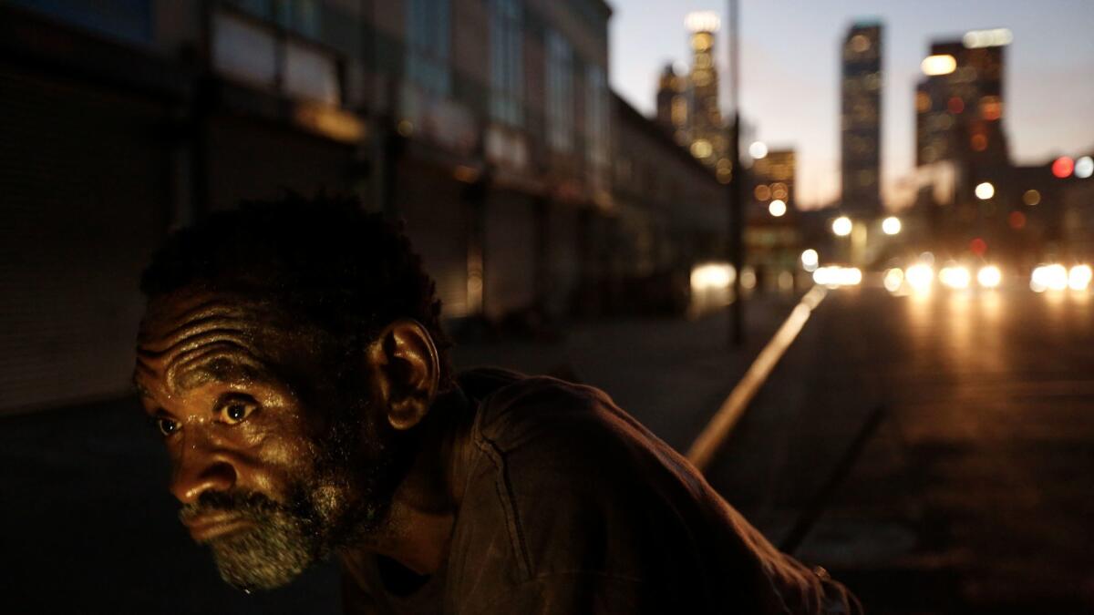 John Lee Norman, who is homeless, leans on his shopping cart along 4th Street in Los Angeles' skid row.