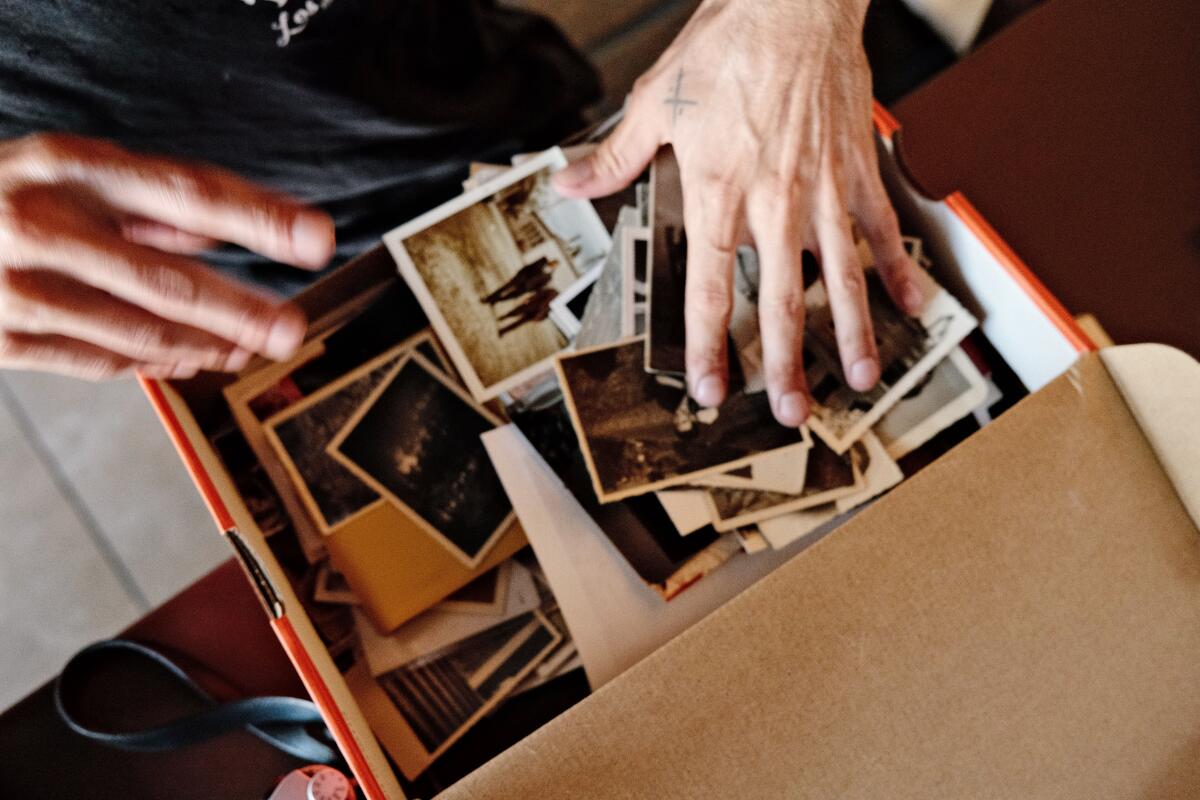 An overhead photo of Rob Hoffman's hands sorting through a shoebox of photos, many of them black-and-white, at Osteria Mamma