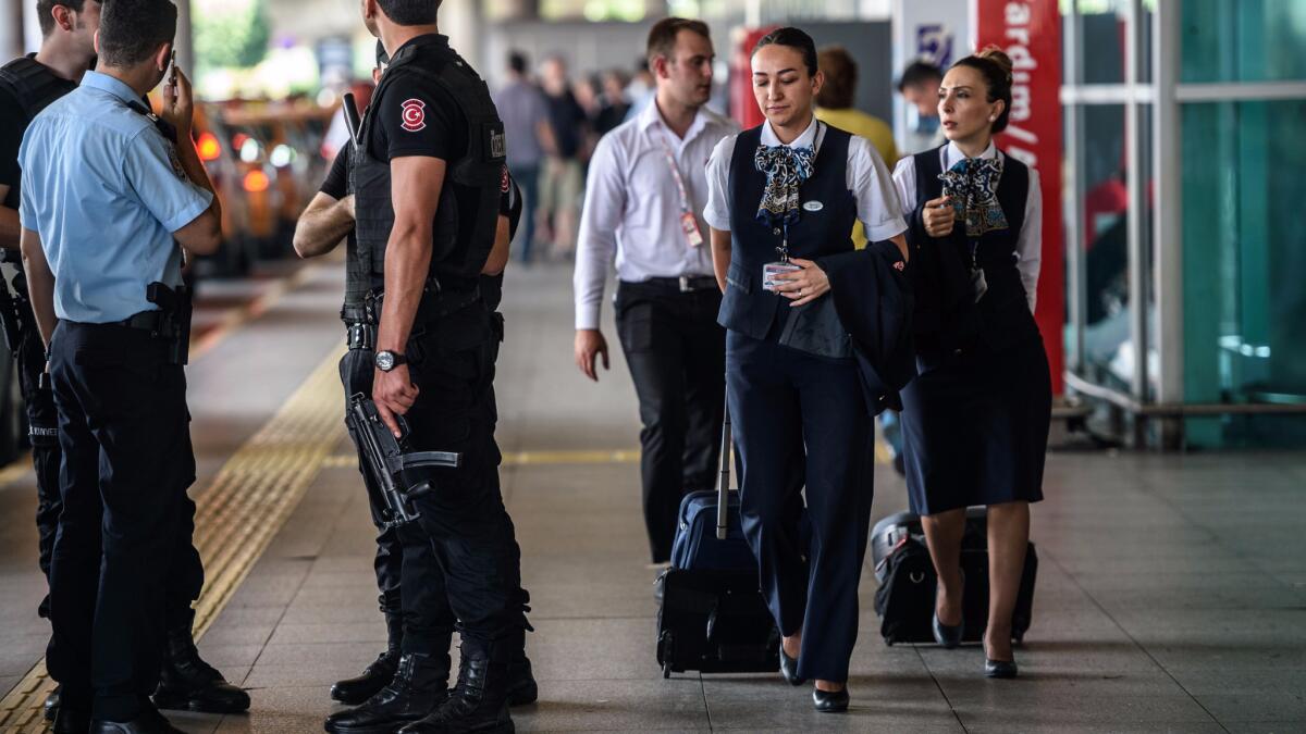 Turkish police officers stand guard as flight attendants walk by at Ataturk Airport in Istanbul on July 1, 2016.