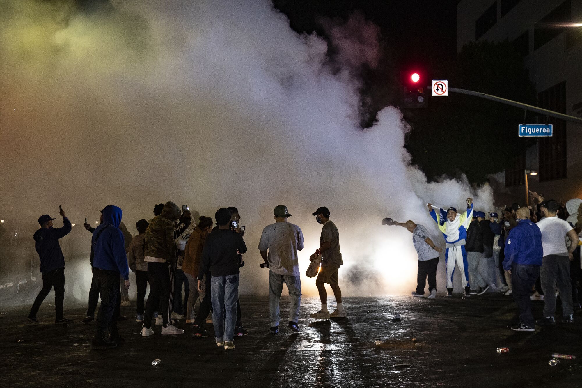People block an intersection as a car spinning its tires creates a wall of smoke.